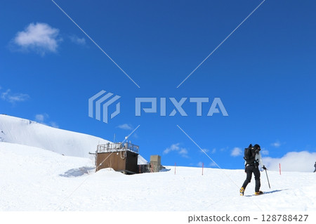 Backcountry skiers climbing snowy mountain in Hakuba Happo-one, Northern Alps, Japan 128788427