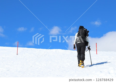 Backcountry skiers climbing snowy mountain in Hakuba Happo-one, Northern Alps, Japan Backcountry skiers climbing snowy mountain in Hakuba Happo-one, Northern Alps, Japan 128788429