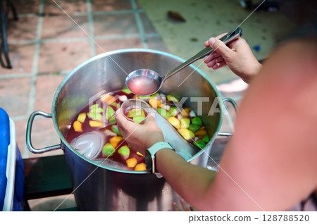 Person Serving Refreshing Homemade Fruit Sangria in an Outdoor Gathering Person Serving Refreshing Homemade Fruit Sangria in an Outdoor Gathering 128788520