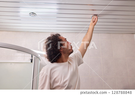 A Hand is Reaching for the Ceiling Fixture in the Interior Space of the Home or Room A Hand is Reaching for the Ceiling Fixture in the Interior Space of the Home or Room 128788848