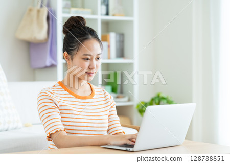 A young woman using a computer at home A young woman using a computer at home 128788851