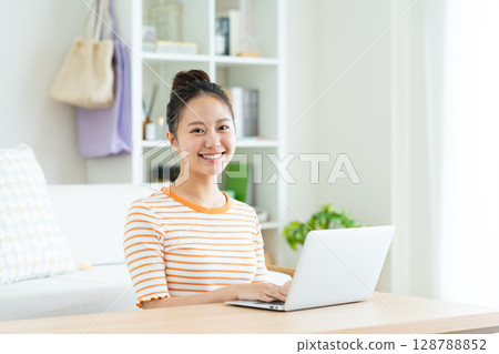 A young woman using a computer at home A young woman using a computer at home 128788852