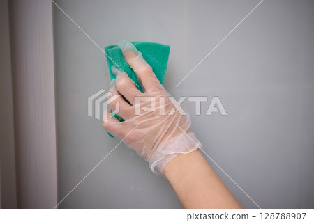A person is cleaning a window with a spray bottle and cloth for clarity and shine 128788907