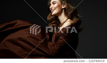 Elegant portrait of a smiling woman in luxurious brown attire, showcasing timeless beauty and style Elegant portrait of a smiling woman in luxurious brown attire, showcasing timeless beauty and style 128789419