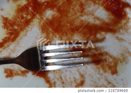 Empty dirty white plate with tomato sauce or ketchup on it. 128789680