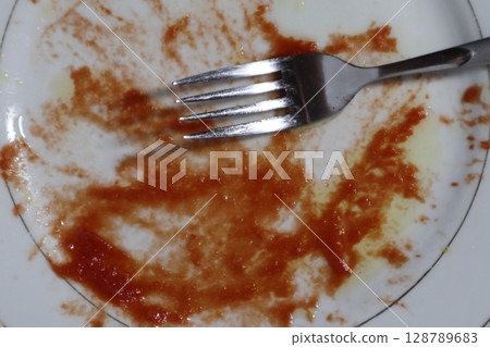 Empty dirty white plate with tomato sauce or ketchup on it. Empty dirty white plate with tomato sauce or ketchup on it. 128789683