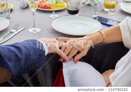 Closeup of Intertwined Hands Featuring Wedding Rings, Symbolizing a Deep Emotional Connection 128790282