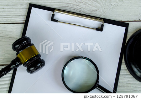 View of blank paper, magnifying glass and gavel with customizable space for text. View of blank paper, magnifying glass and gavel with customizable space for text. 128791067
