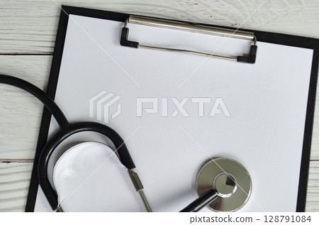 Medical clipboard with stethoscope on white background with customizable space for text or message. 128791084