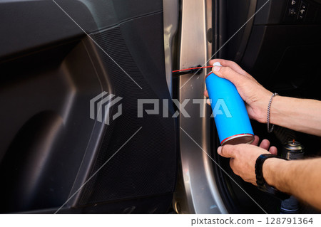 Applying spray lubricant to car door hinges helps keep them functioning smoothly Applying spray lubricant to car door hinges helps keep them functioning smoothly 128791364