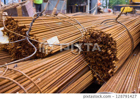 Stacked steel rods are prominently observed at a bustling construction site in progress Stacked steel rods are prominently observed at a bustling construction site in progress 128791427