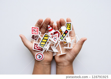 Child hands holding assorted miniature road signs on white background 128791925