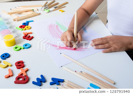 Child drawing with colored pencils and alphabet letters on white table Child drawing with colored pencils and alphabet letters on white table 128791940