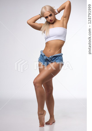 A Stylish and Fashionable Model Posing Confidently in Denim Shorts with Long, Flowing Blonde Hair 128791999
