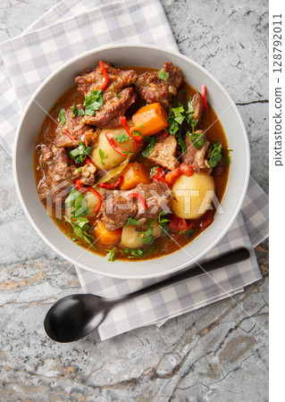 Indonesian Spiced Beef Stew Semur Daging closeup in the bowl on the table. Vertical top view Indonesian Spiced Beef Stew Semur Daging closeup in the bowl on the table. Vertical top view 128792011