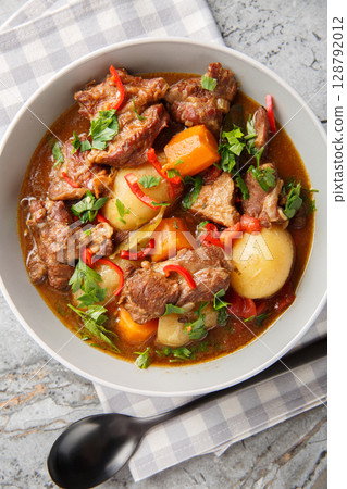 Beef stew Semur Daging with potatoes, carrot and a rich sweet-spiced soy sauce-based broth closeup in the bowl. Vertical top view 128792012