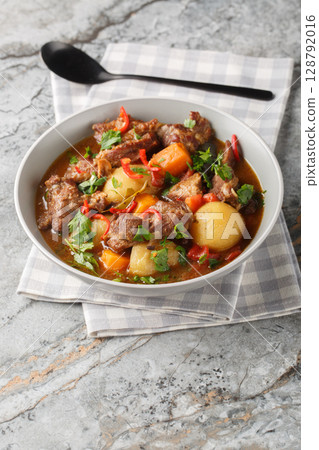 Beef stew Semur Daging with potatoes, carrot and a rich sweet-spiced soy sauce-based broth closeup in the bowl. Vertical 128792016