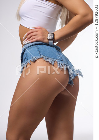 A Stylish and Fashionable Model Posing Confidently in Denim Shorts with Long, Flowing Blonde Hair 128792033