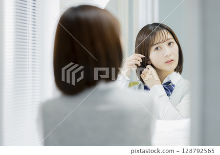 High school girl looking at a mirror High school girl looking at a mirror 128792565