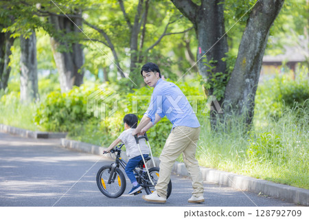 Parent and child practicing riding a bicycle 128792709