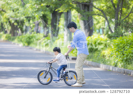 Parent and child practicing riding a bicycle Parent and child practicing riding a bicycle 128792710