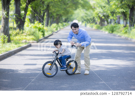Parent and child practicing riding a bicycle Parent and child practicing riding a bicycle 128792714