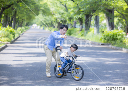 Parent and child practicing riding a bicycle 128792716
