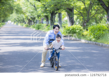 Parent and child practicing riding a bicycle 128792718