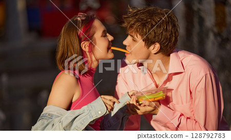Young couple enjoying fresh vegetables lovingly outside in warm light 128792783