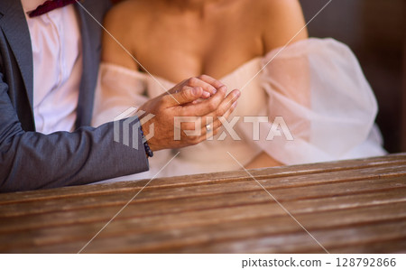 A Romantic Wedding Couple Holding Hands in Their Elegant Attire, Radiating Joy and Love 128792866