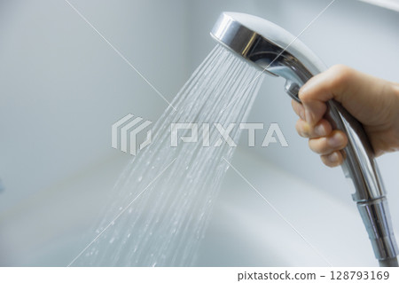 Woman's hand holding a shower head Woman's hand holding a shower head 128793169