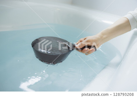 Woman's hand scooping hot water 128793208