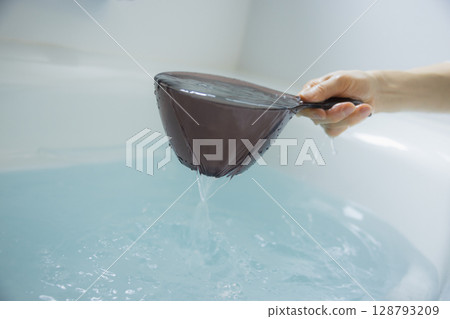 Woman's hand scooping hot water 128793209