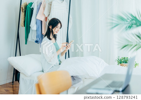 Woman using smartphone in bedroom Woman using smartphone in bedroom 128793241