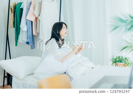 A young lady who manipulates a smartphone in bed A young lady who manipulates a smartphone in bed 128793247