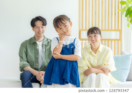 年輕的父母和孩子在客廳放鬆，孩子思考 128793347