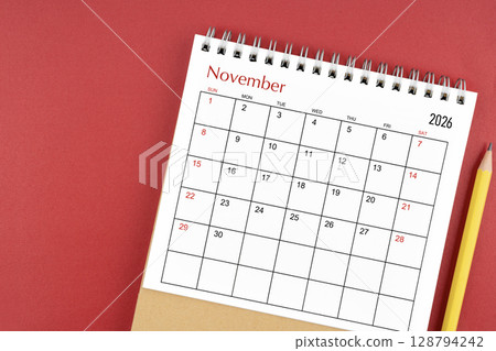 November 2026 desk calendar and pencil on red color background. 128794242