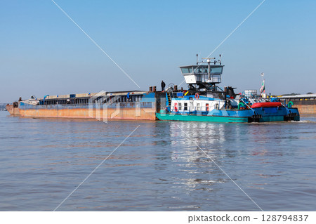 Rear view of a blue and white tugboat pushing a barge on Danube river, 128794837