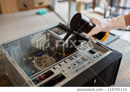 A man cleans a computer case with a vacuum in a bright room, stressing workspace tidiness A man cleans a computer case with a vacuum in a bright room, stressing workspace tidiness 128795118