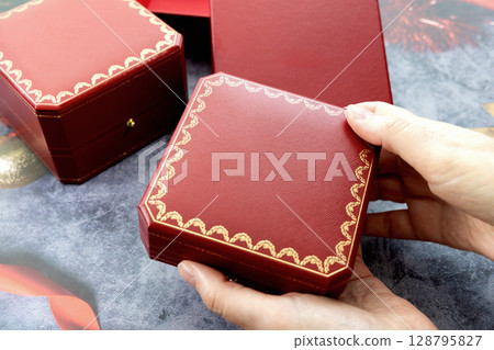 Female hands holding a red jewelry box 128795827