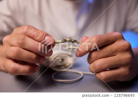 Carefully Repairing a Damaged Charging Cable with Skillful Hands for Best Results and Safety 128796695