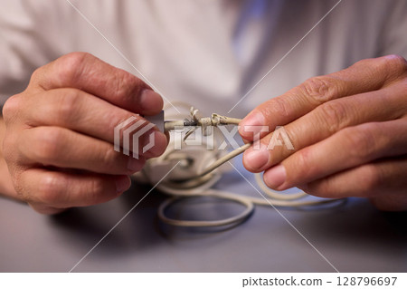 Carefully Repairing a Damaged Charging Cable with Skillful Hands for Best Results and Safety 128796697