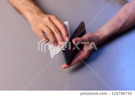 Cleaning a smartphone screen with a tissue needs attention for optimal hygiene and care Cleaning a smartphone screen with a tissue needs attention for optimal hygiene and care 128796730