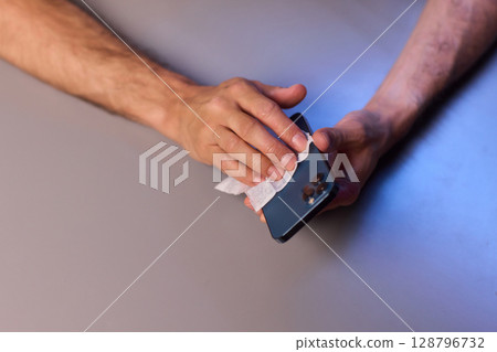 Cleaning a smartphone screen with a tissue needs attention for optimal hygiene and care 128796732