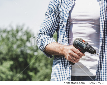 Handsome man, screwdriver and work clothes Handsome man, screwdriver and work clothes 128797536