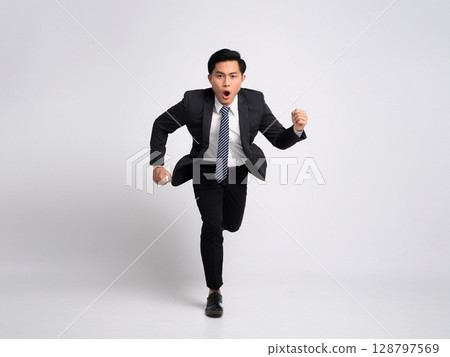 A businessman in a suit running and jumping 128797569
