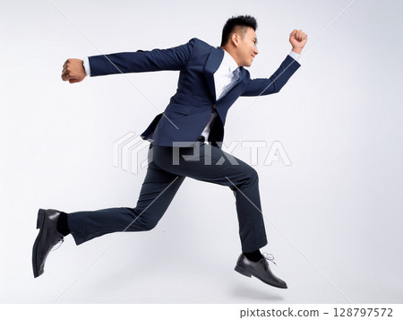 A businessman in a suit running and jumping 128797572