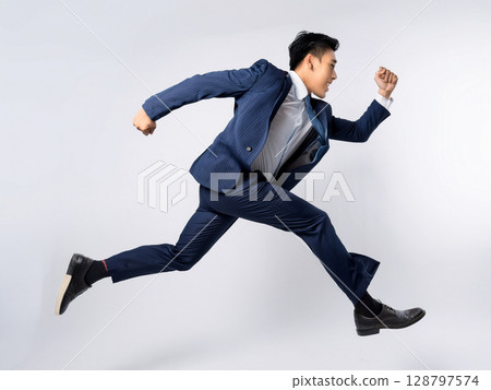 A businessman in a suit running and jumping 128797574