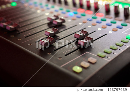 Closeup image of a hand mixing sounds on a control board, showcasing an audio technicians work 128797689