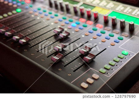 Closeup image of a hand mixing sounds on a control board, showcasing an audio technicians work 128797690